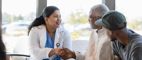 Female doctor shakes elderly patient's hand.